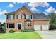 Charming two-story brick home featuring a well-manicured lawn, lovely landscaping, and a three car garage at 3760 Ansley Park Dr, Suwanee, GA 30024