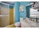 Bathroom featuring blue walls, a shower with glass door, vanity and sink, and decorative shelf at 493 James Street Sw, Lilburn, GA 30047