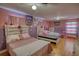 Bright bedroom with pink and purple walls, hardwood flooring, and two beds at 493 James Street Sw, Lilburn, GA 30047