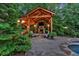 Outdoor entertainment area with a covered pavilion, stone fireplace, comfortable seating, and lush greenery at 1220 Waterfall Nw Ln, Acworth, GA 30101