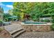 A backyard swimming pool and spa area with a stone surround and professionally landscaped yard at 1220 Waterfall Nw Ln, Acworth, GA 30101