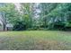 Large green backyard featuring lush green trees and well-maintained grass at 1706 Brandon Lee Sw Way, Marietta, GA 30008