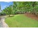 Well maintained backyard with a large green lawn, mature trees, and a stone walkway at 2010 Pearwood Path, Roswell, GA 30076