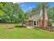 Backyard of home featuring lush green lawn, mature trees, brick accents, and a patio at 2010 Pearwood Path, Roswell, GA 30076