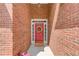 Close-up of a red brick entryway featuring a vibrant red door with decorative wreath and a patterned welcome mat at 3585 Berkeley Park Ct, Duluth, GA 30096