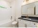 Bathroom featuring a white tub and shower with a white vanity and black countertop and gold hardware at 7080 Driskell Cir, Cumming, GA 30041