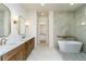 Elegant bathroom featuring double vanity, marble countertops, soaking tub, and tiled shower with glass door at 7080 Driskell Cir, Cumming, GA 30041