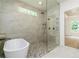 Bathroom featuring a soaking tub, tiled shower with glass door, and window for natural lighting at 7080 Driskell Cir, Cumming, GA 30041