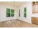 Sunlit dining area with modern chandelier, wood floors, and backyard view at 7080 Driskell Cir, Cumming, GA 30041