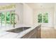 Marble kitchen island with stainless sink overlooking the outdoor deck at 7080 Driskell Cir, Cumming, GA 30041