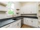 Charming kitchenette with white cabinets, granite countertop, stainless appliances, and decorative floating shelves at 7080 Driskell Cir, Cumming, GA 30041