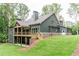 Spacious home featuring a rear deck, lower-level patio, and green exterior nestled into a hillside lot at 7080 Driskell Cir, Cumming, GA 30041