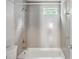 Bathroom featuring gray tile walls, a tub with shower, and a small window at 1891 8Th St, Atlanta, GA 30341