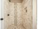 Tiled shower with a decorative accent stripe, built-in niche, and stone flooring, providing a spa-like experience at 3286 Crawford Cir, Marietta, GA 30066