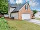 View of brick home showcasing the side yard and attached two-car garage at 3190 Water Brook Sw Dr, Conyers, GA 30094