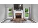Close-up of a cozy fireplace with a stone surround, mantle, and backyard views from surrounding windows at 3190 Water Brook Sw Dr, Conyers, GA 30094