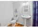 Half-bathroom featuring a pedestal sink, hardwood floors, toilet, and blue shower curtain at 827 Holly Rdg, Canton, GA 30115