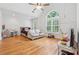 Spacious bedroom with hardwood floors, a ceiling fan, natural light from the large arched window, and lounge furniture at 827 Holly Rdg, Canton, GA 30115