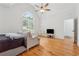 Spacious bedroom with hardwood floors, a ceiling fan, natural light from the large arched window, and lounge furniture at 827 Holly Rdg, Canton, GA 30115