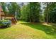 Lush, green backyard featuring mature trees, blooming hydrangeas, and a wooden deck at 1275 Kelly Nelson Dr, Lawrenceville, GA 30043