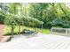 White deck featuring a pergola with an outdoor dining set surrounded by shady trees and green grass at 2197 Fairway Ne Cir, Brookhaven, GA 30319