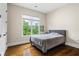 Cozy bedroom with hardwood floors, a large window with blinds, and a comfortable bed at 241 Russell Rd, Lawrenceville, GA 30043