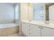 Bathroom featuring a double sink vanity and a separate tub with tile surround at 1666 Oakbrook Lake Dr, Norcross, GA 30093