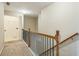 Upstairs hallway with carpeted floor and wood banister, next to the laundry room at 1666 Oakbrook Lake Dr, Norcross, GA 30093
