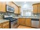 An open kitchen showcasing wood cabinets, stainless steel appliances, granite counters and a mosaic tile backsplash at 1666 Oakbrook Lake Dr, Norcross, GA 30093