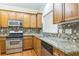 The kitchen features wood cabinets, a stainless steel oven, mosaic tile backsplash, and granite countertops at 1666 Oakbrook Lake Dr, Norcross, GA 30093