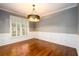 Elegant dining room with hardwood flooring, wainscoting detail, and a modern chandelier at 4916 Gathering Pl, Suwanee, GA 30024