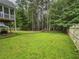 Large grassy backyard with trees, a white wooden fence, and a house in the background at 111 Bexley Ln, Douglasville, GA 30134