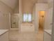Main bathroom featuring a soaking tub, glass shower, neutral tile and dual sinks at 111 Bexley Ln, Douglasville, GA 30134