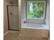 Bathroom featuring a tub, shower, and window offering a view of greenery at 7593 Watson Bay Ct, Stone Mountain, GA 30087