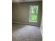 A simple, carpeted bedroom with a large window offering natural light and a view of lush greenery at 7593 Watson Bay Ct, Stone Mountain, GA 30087
