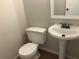 Powder room featuring a pedestal sink and toilet, illuminated by a decorative mirror at 7593 Watson Bay Ct, Stone Mountain, GA 30087