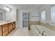 Bright bathroom featuring a soaking tub with tile surround, tile flooring, and a view into the bedroom at 4495 Hedgewood Dr, Cumming, GA 30041