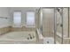 Bright bathroom featuring a soaking tub with tile surround and a glass enclosed shower at 4495 Hedgewood Dr, Cumming, GA 30041