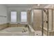 This bathroom boasts a soaking tub, tiled shower and floors, and natural light from the windows at 4495 Hedgewood Dr, Cumming, GA 30041