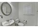 Elegant powder room featuring a round mirror and white fixtures at 4495 Hedgewood Dr, Cumming, GA 30041