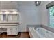 Bathroom with granite countertop vanity, soaking tub, and large windows overlooking backyard at 2530 Ashbourne Dr, Lawrenceville, GA 30043