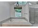 Bathroom with large soaking tub surrounded by travertine tile and a glass enclosed shower at 2530 Ashbourne Dr, Lawrenceville, GA 30043
