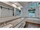 Bright bathroom with double vanity, granite counters, mirrors, soaking tub, and large windows overlooking backyard at 2530 Ashbourne Dr, Lawrenceville, GA 30043