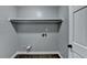 Simple laundry area with overhead shelf, gray walls, dark trim and hardwood flooring at 2530 Ashbourne Dr, Lawrenceville, GA 30043