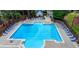 A bright blue community pool with lounge chairs, umbrellas, and a bath house in a relaxing outdoor space at 2530 Ashbourne Dr, Lawrenceville, GA 30043