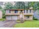 Charming split-level home with a two-car garage, light siding, and a welcoming front yard and stairwell at 2218 Lowtrail Ct, Lithonia, GA 30058