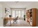 This staged office includes a desk, chair, bookshelf and rug with natural light from the large bay window at 2218 Lowtrail Ct, Lithonia, GA 30058