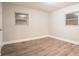 A minimalist bedroom features gray wood-look floors, two windows and a white door leading to the closet at 2817 Burton Nw Rd, Atlanta, GA 30311