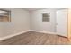 A minimalist bedroom features gray wood-look floors, two windows and a white door leading to the entry at 2817 Burton Nw Rd, Atlanta, GA 30311