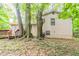 Backyard view of a two-story home with light siding, trees, and a small deck at 5218 Tina Ct, Stone Mountain, GA 30083